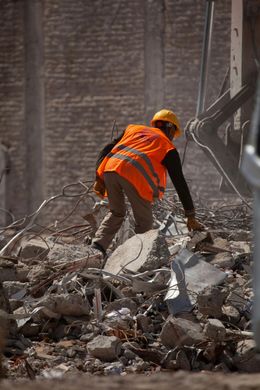 A construction worker is standing in a pile of rocks.