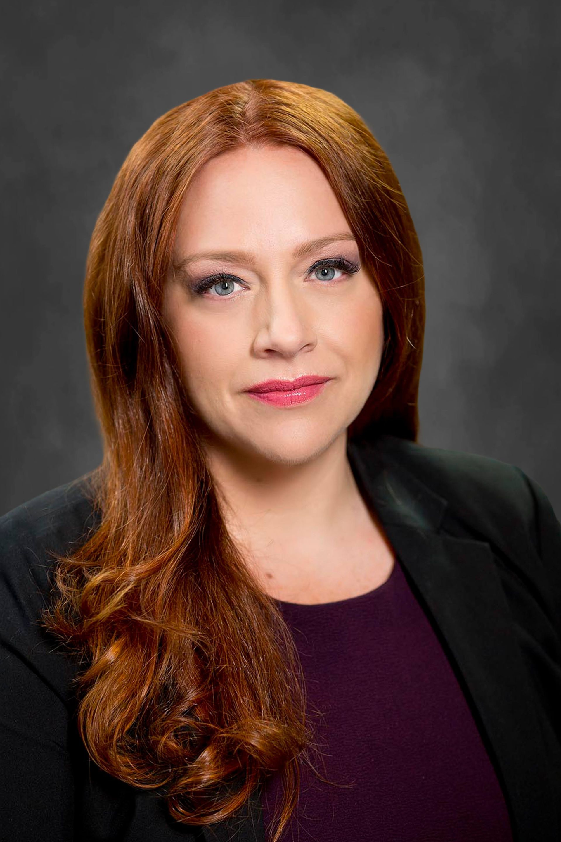 a woman with red hair and blue eyes is wearing a black turtleneck and a black jacket .