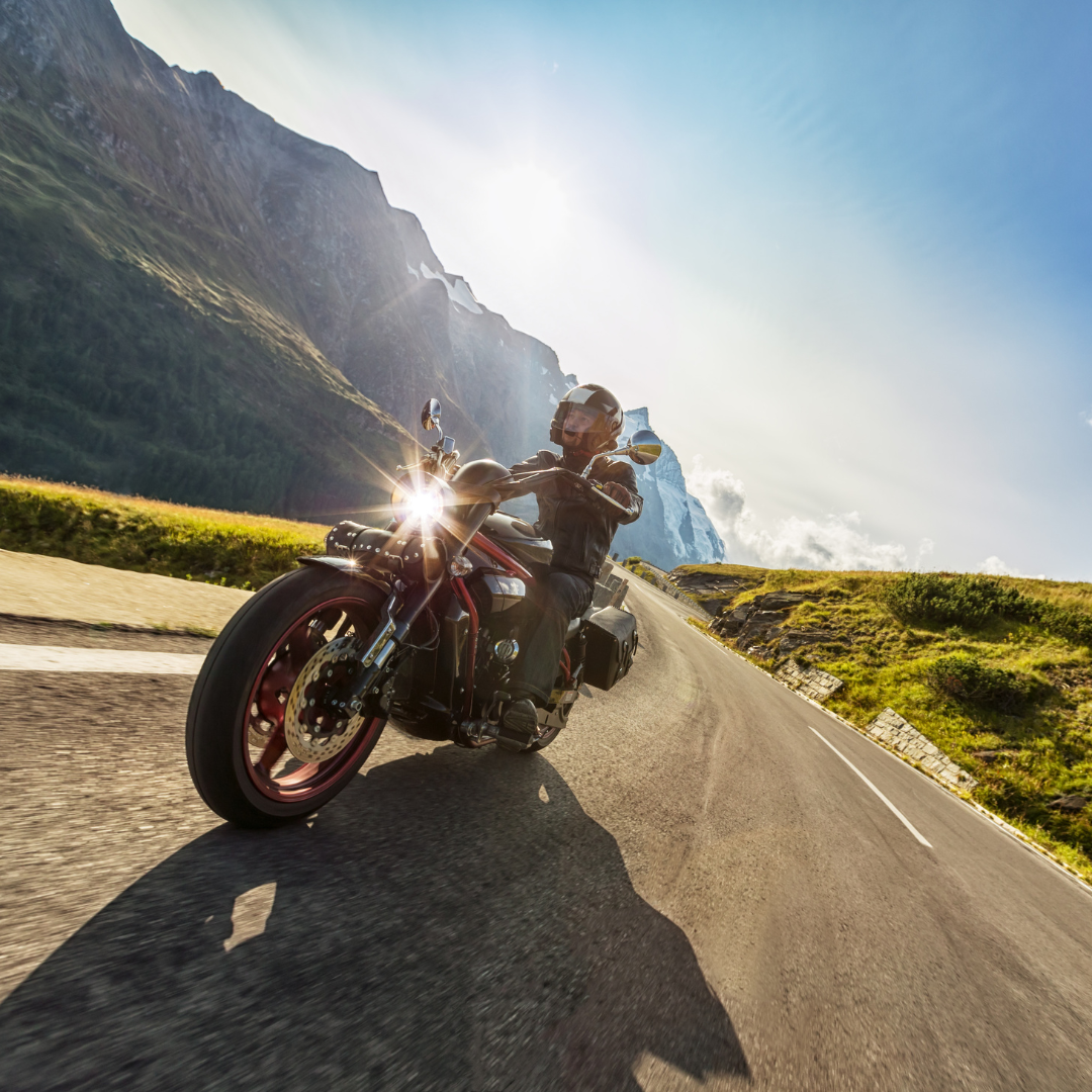 Motorcycle rider on road with mountains in the background