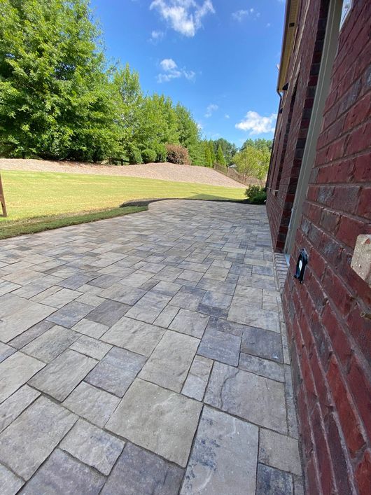 a brick home with a flagstone patio in front of it.