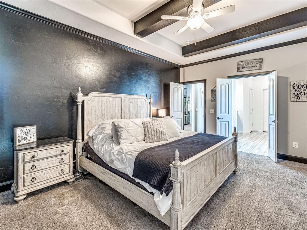 Spacious bedroom with white wood bed, dark accent wall, gray carpet, and ceiling fan.
