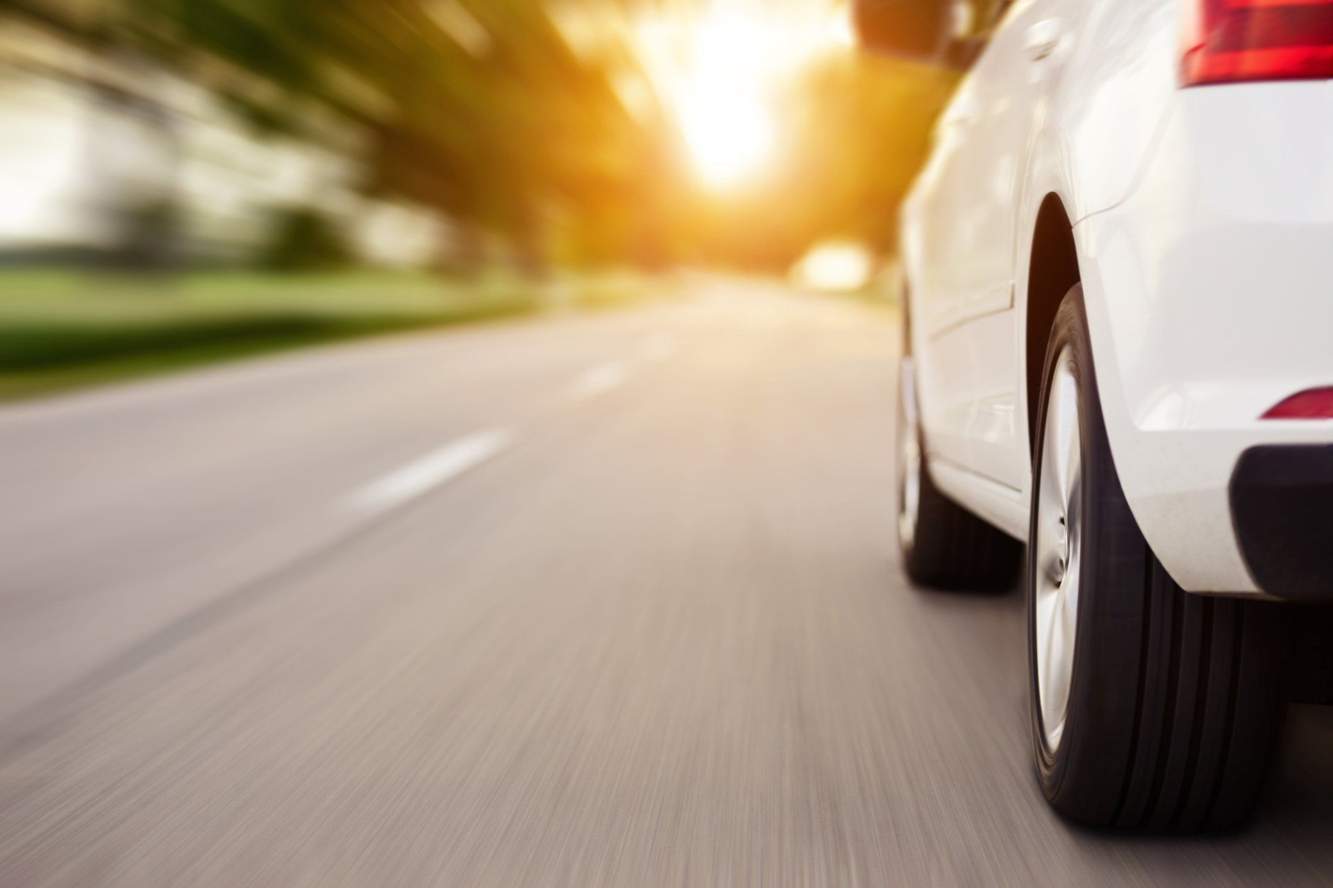 A white car is driving down a road at sunset - Congers, NY - Greg's Autobody