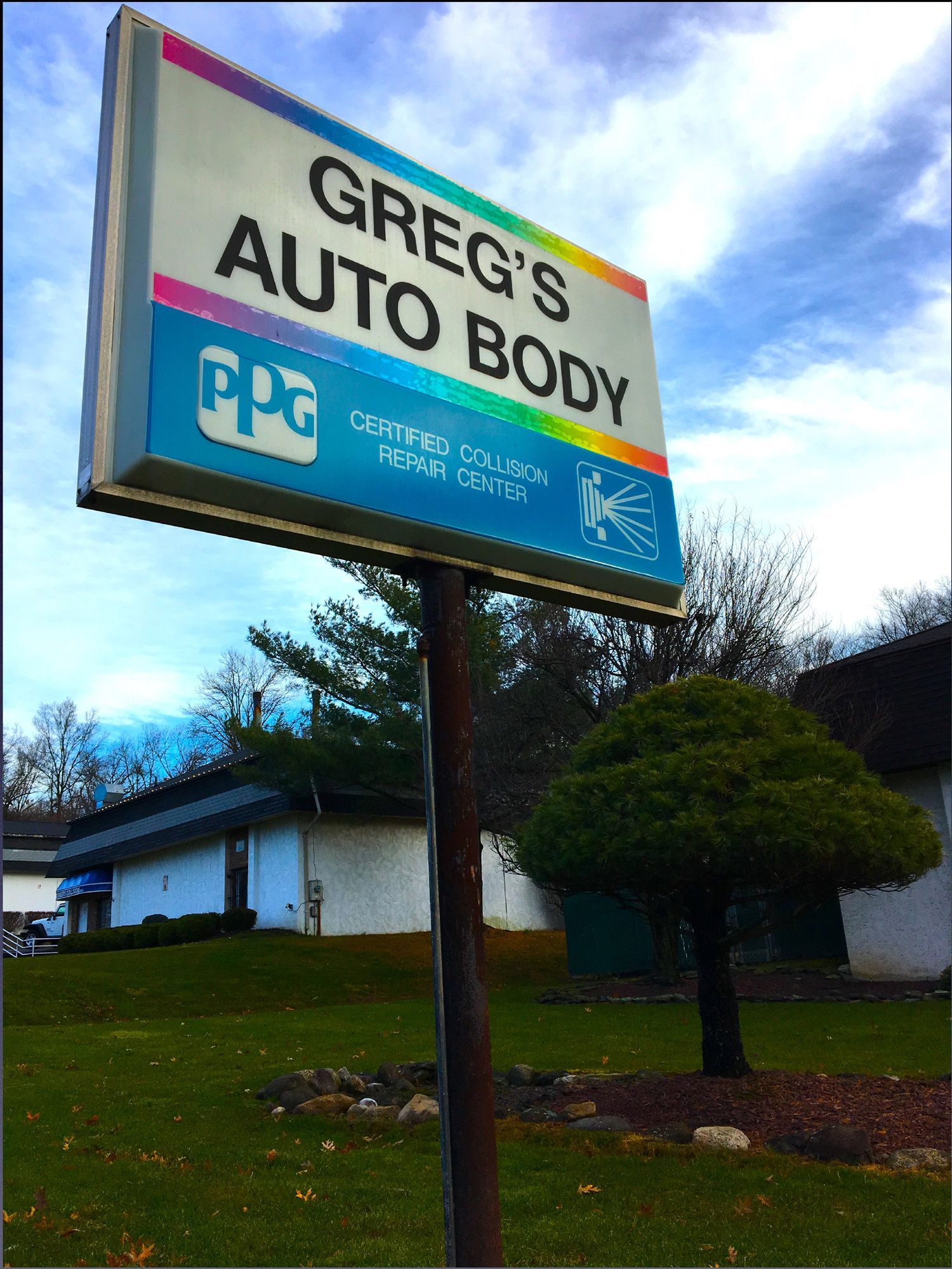 A greg 's auto body sign in front of a house