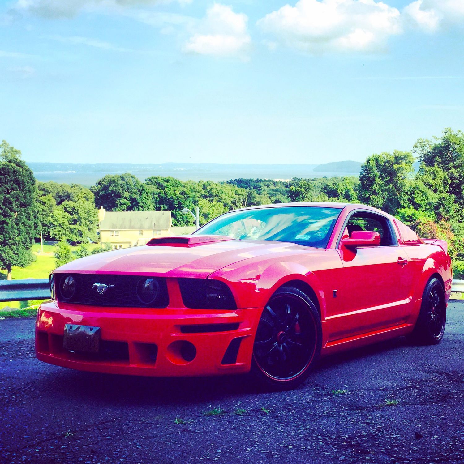 A red mustang is parked on the side of the road