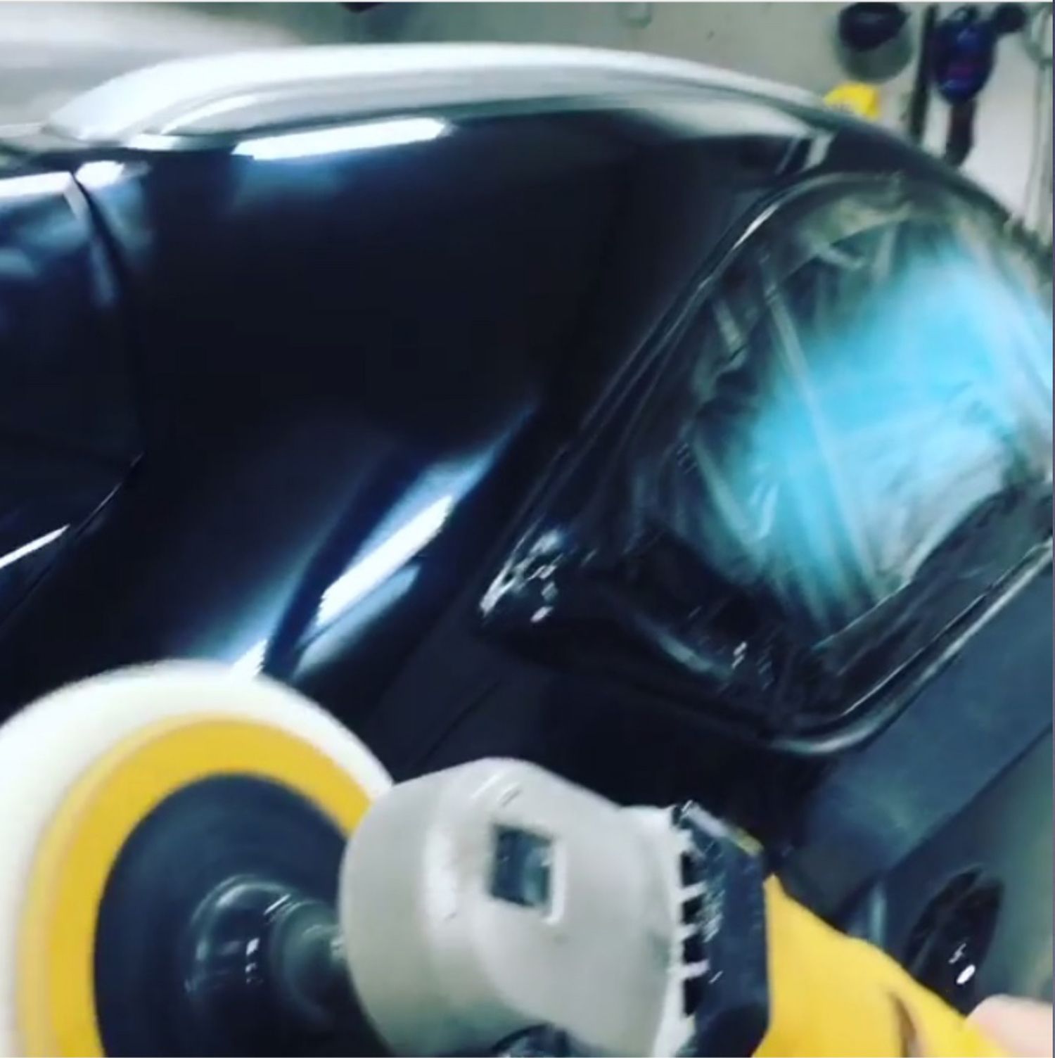 A person is polishing a car with a yellow and white polisher