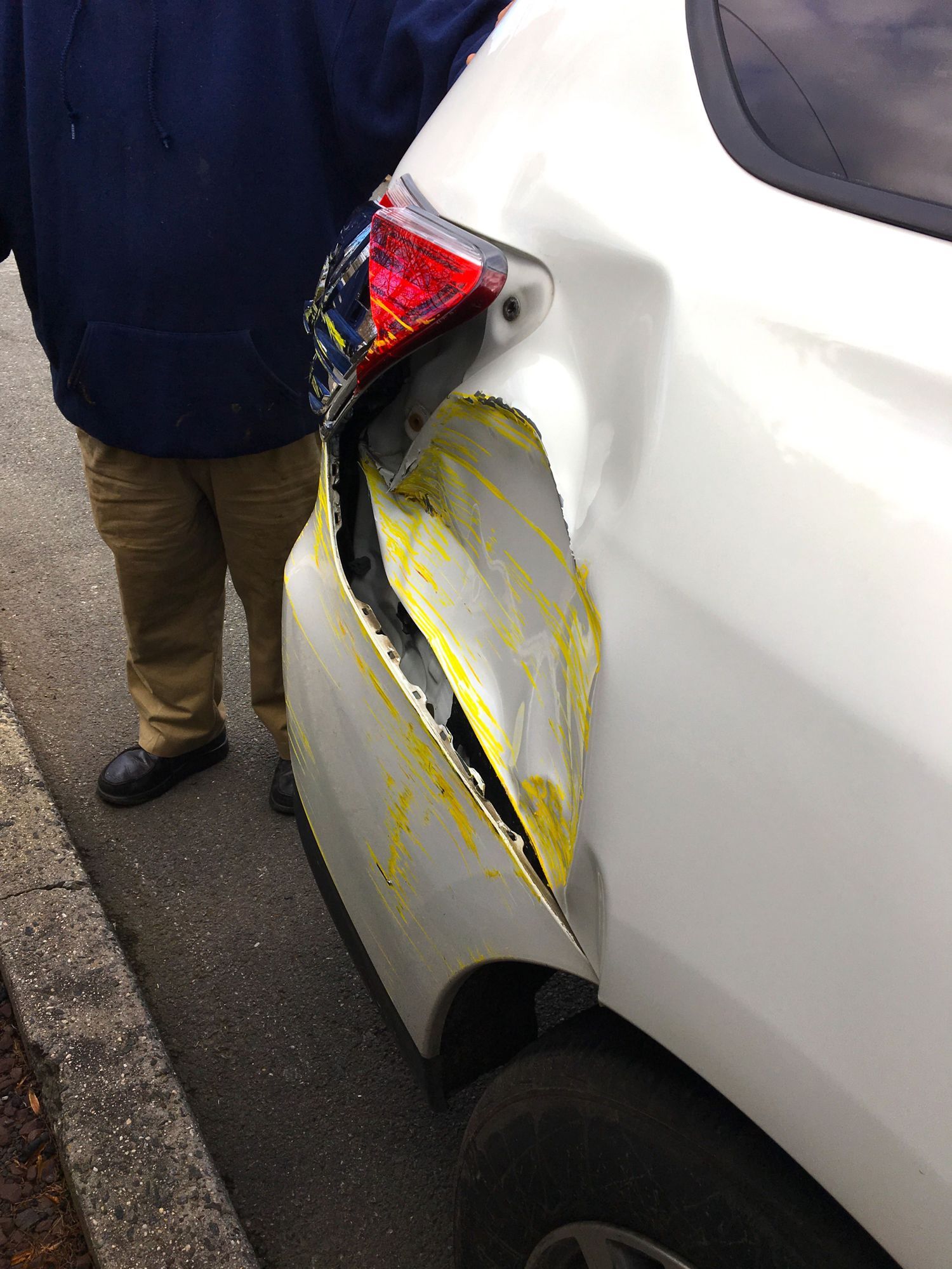 A man is standing next to a damaged white car