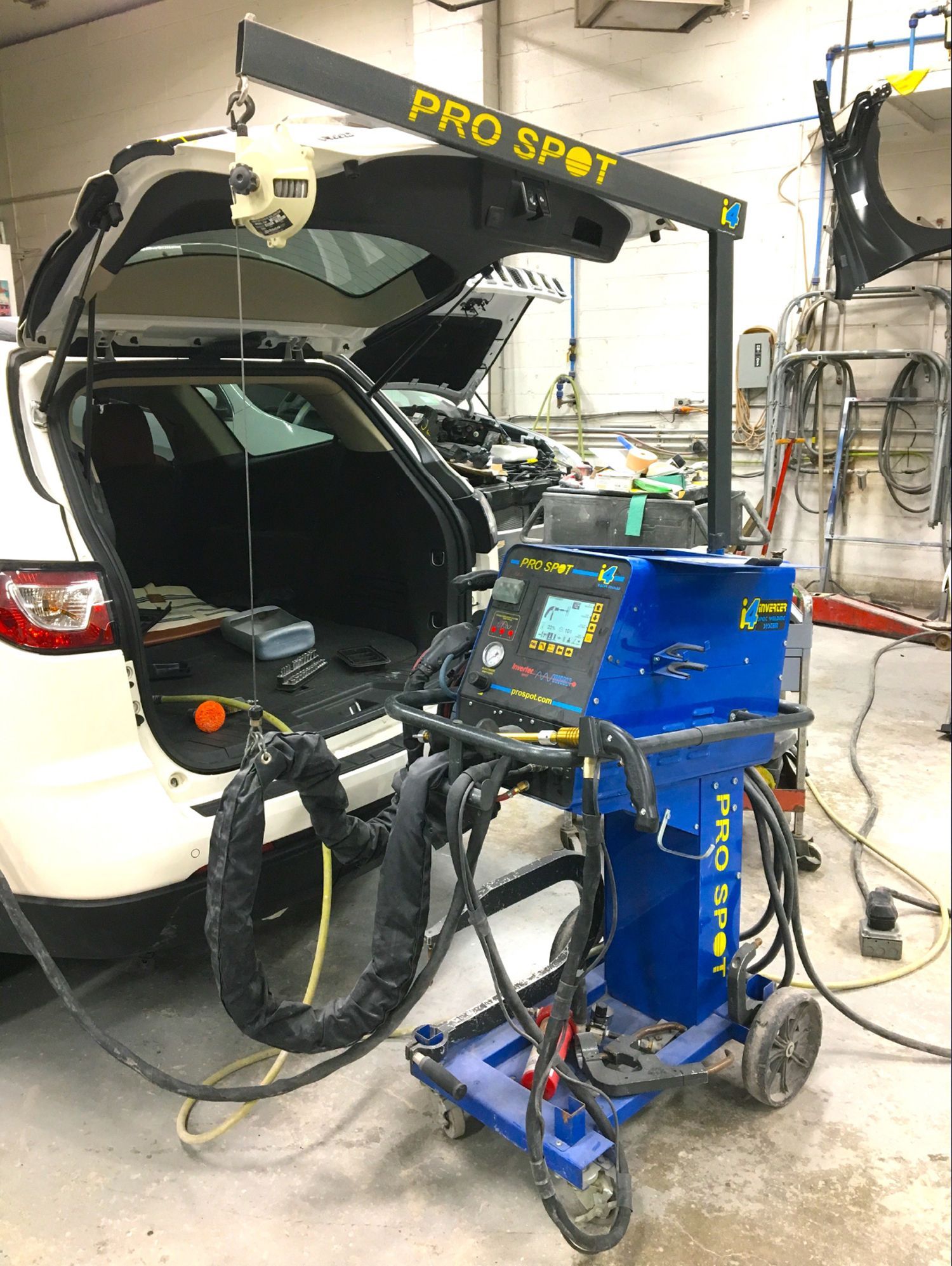 A car is being worked on in a garage with a machine sitting on top of it.
