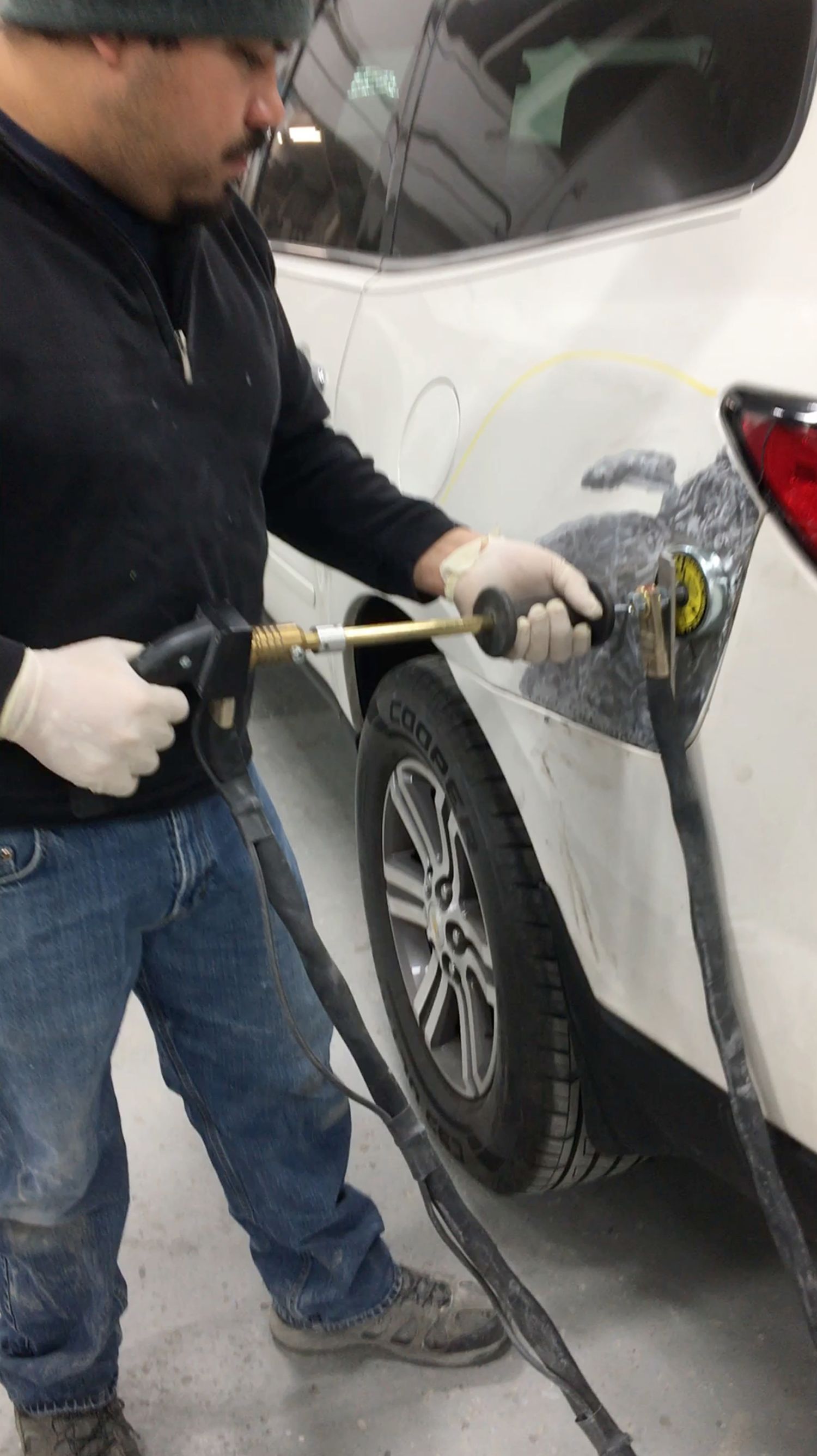 A man is cleaning the side of a car with a hose.