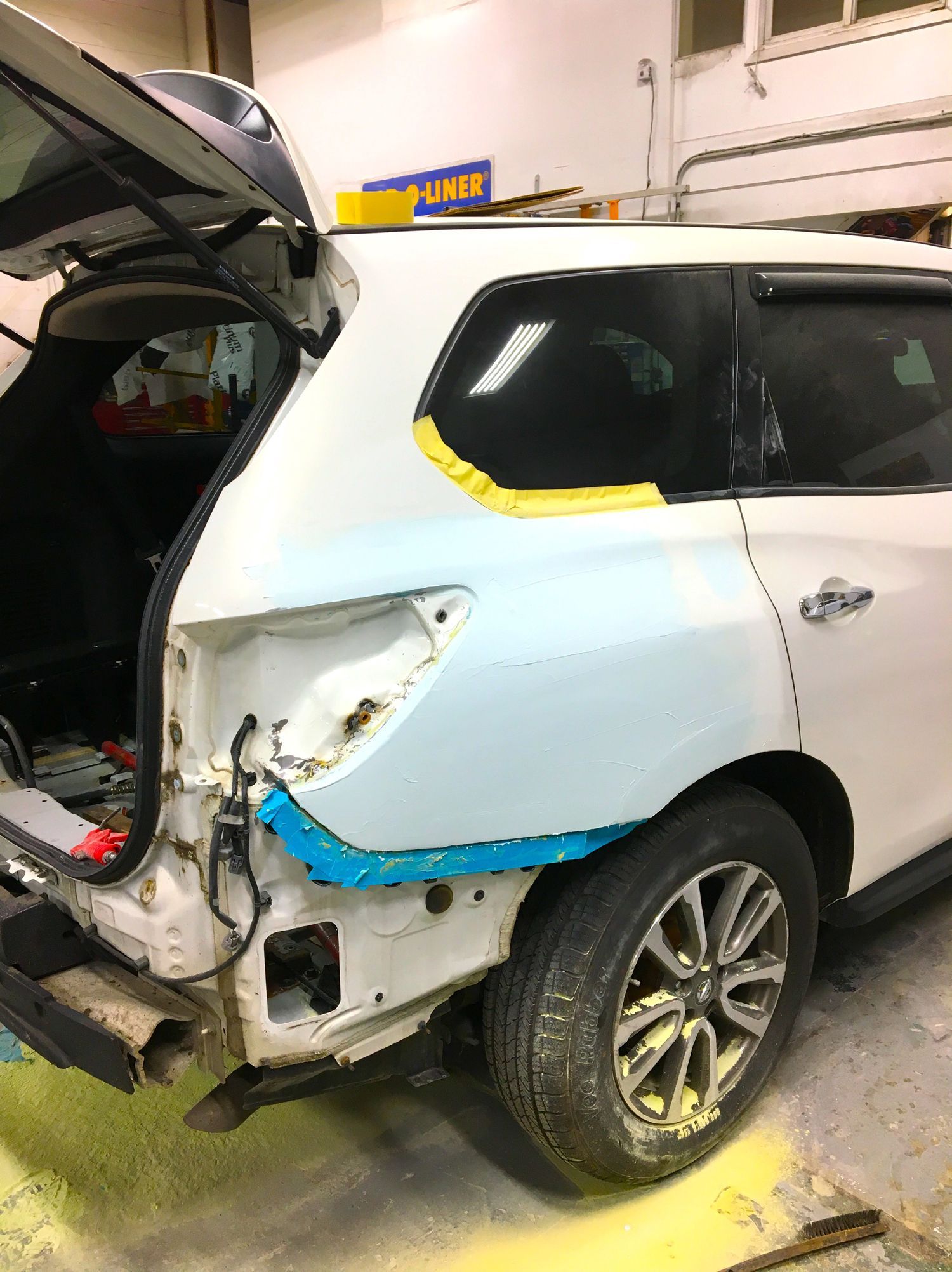 A white suv is being repaired in a garage.
