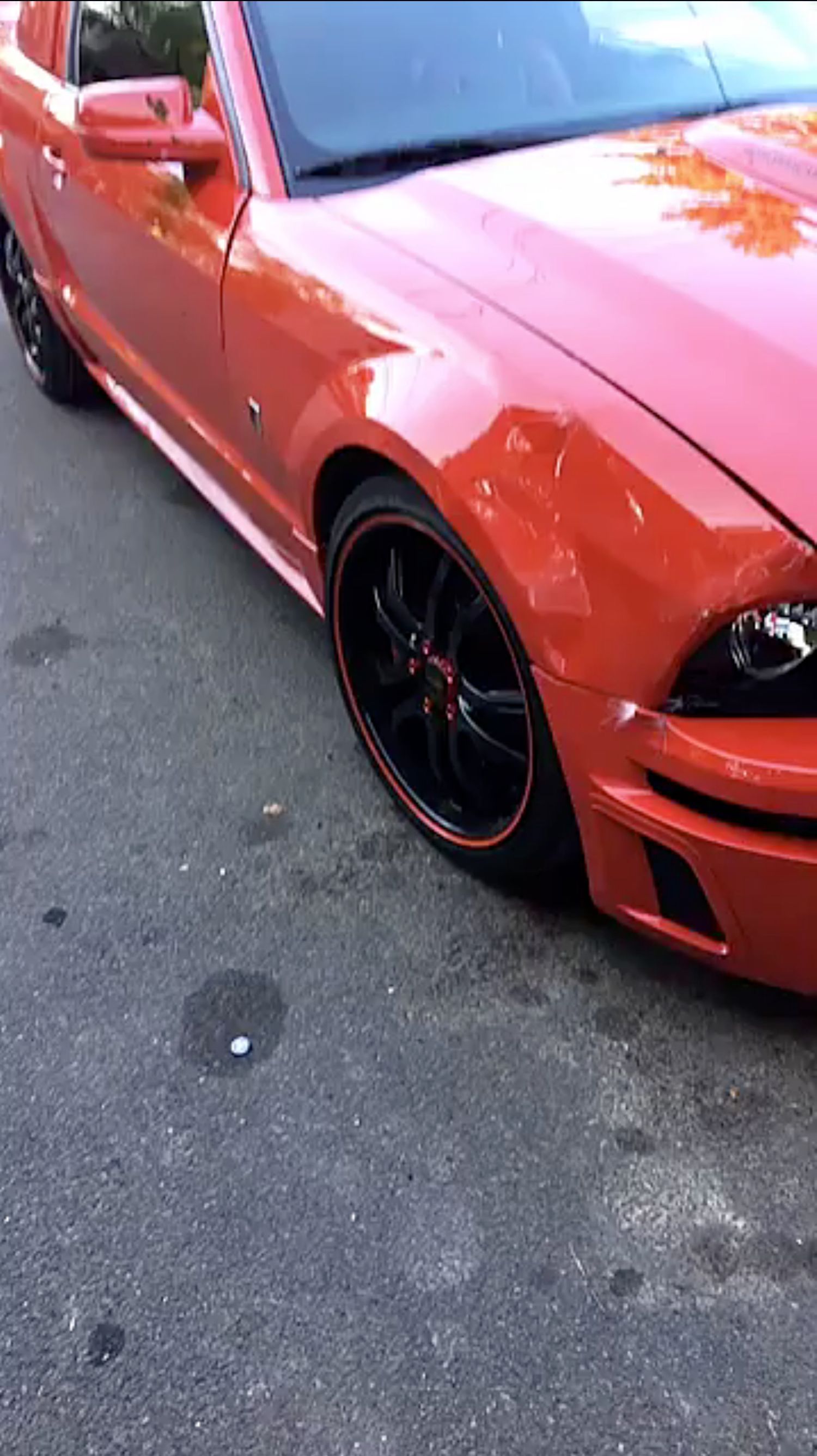 A red mustang is parked on the side of the road.