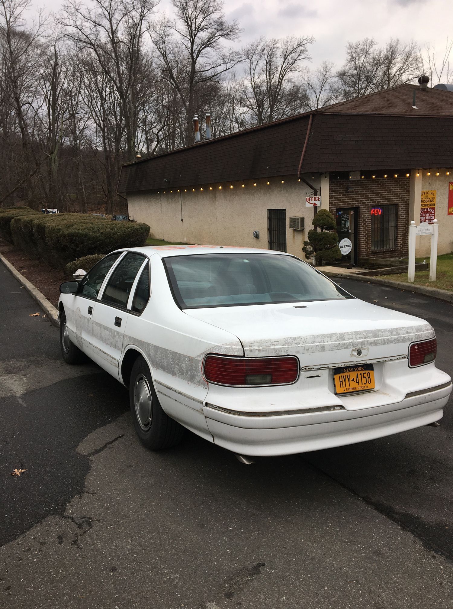 A white car is parked on the side of the road in front of a building.