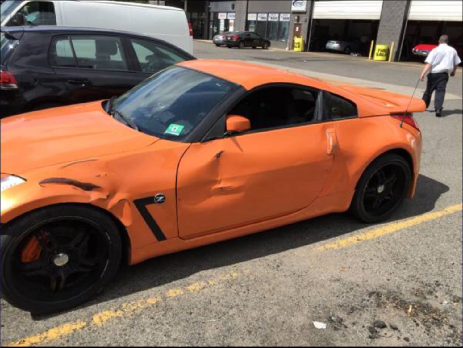A damaged orange sports car is parked in a parking lot