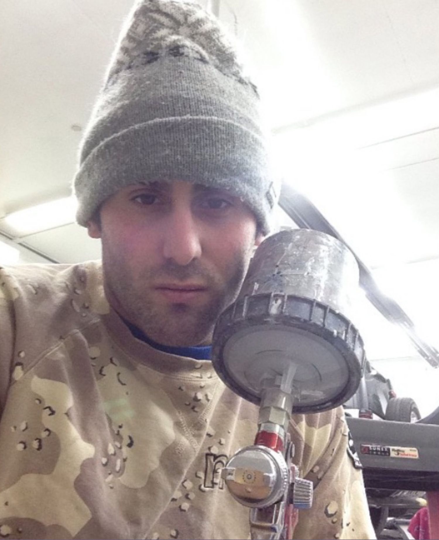 A man wearing a beanie is holding a small object