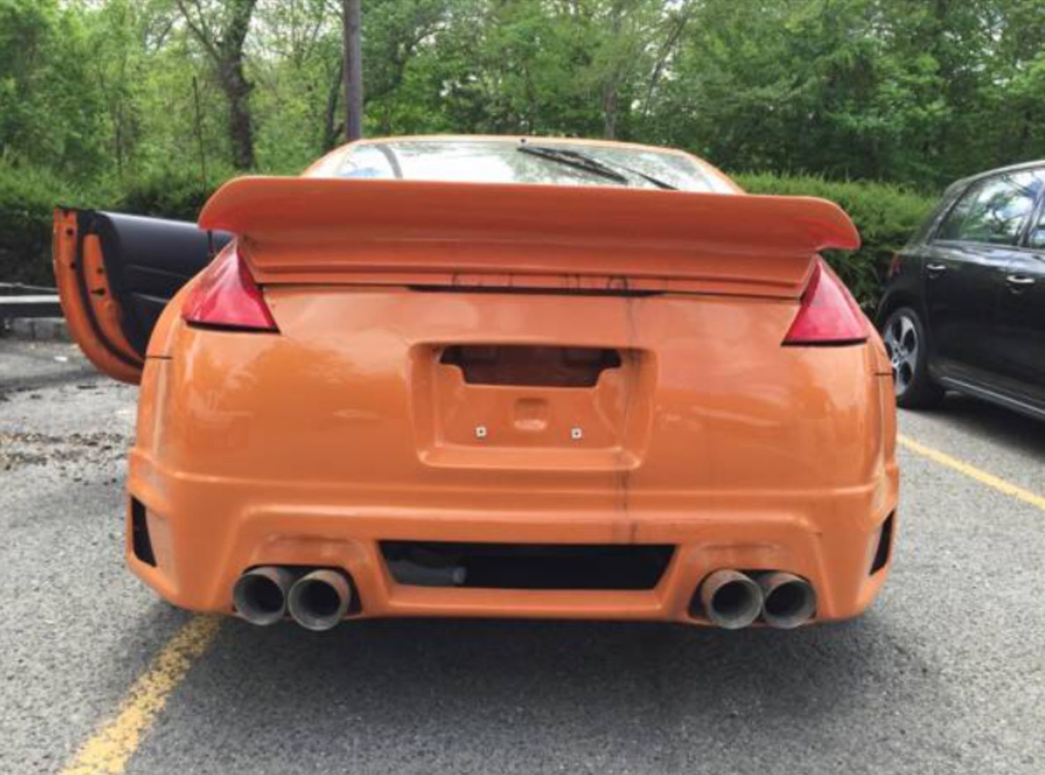 A car with a spoiler on the back is parked in a parking lot.