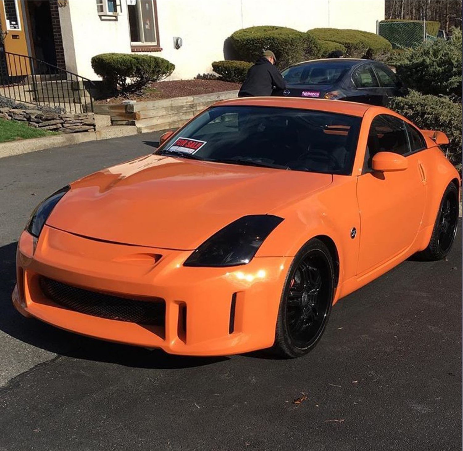 An orange sports car is parked in front of a house