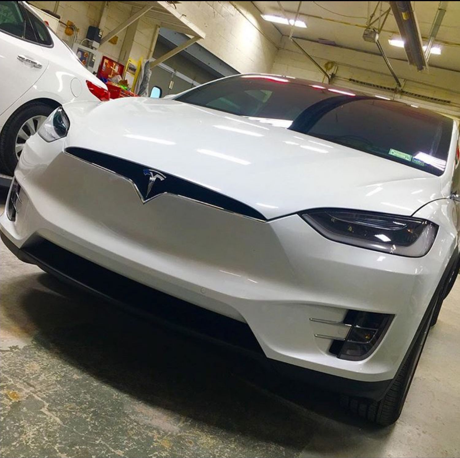 A white tesla model x is parked in a garage