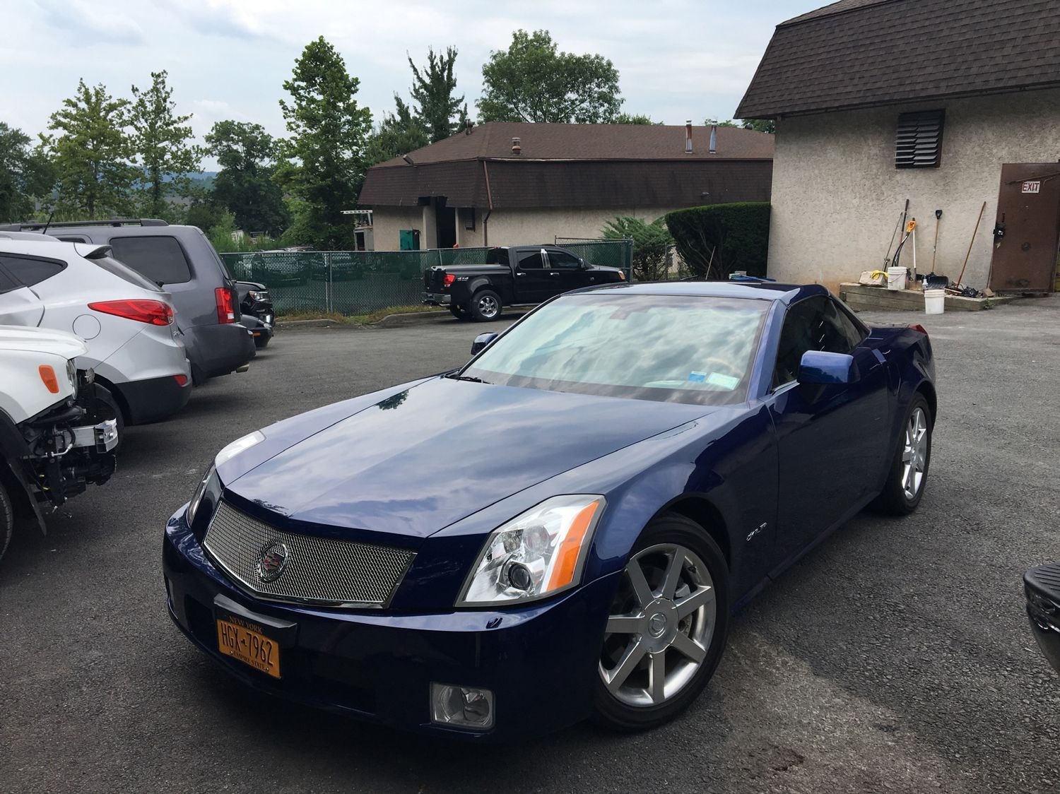 A blue cadillac is parked in a parking lot