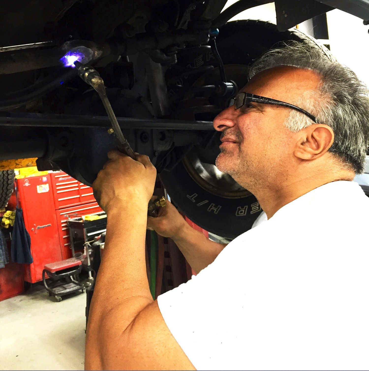 A man wearing glasses is working on a car