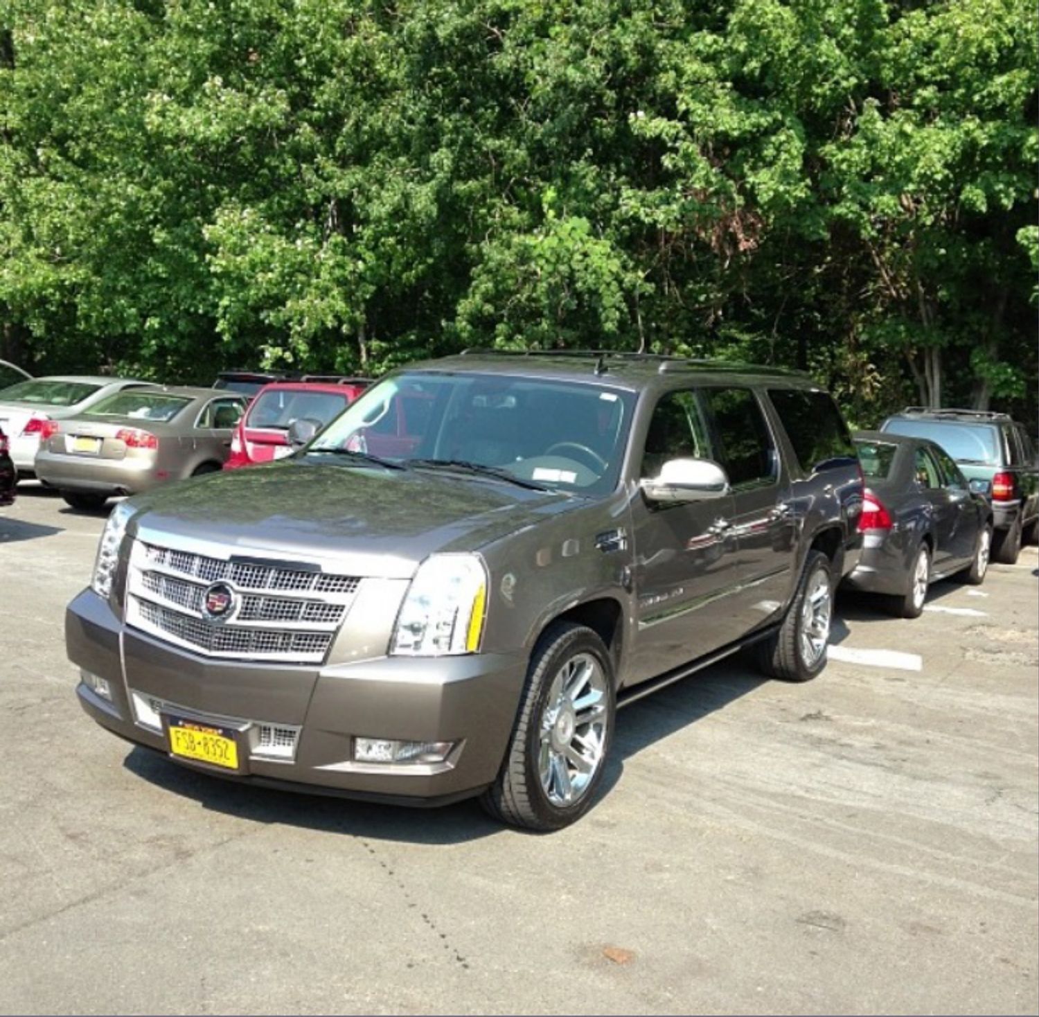A cadillac is parked in a parking lot with other cars