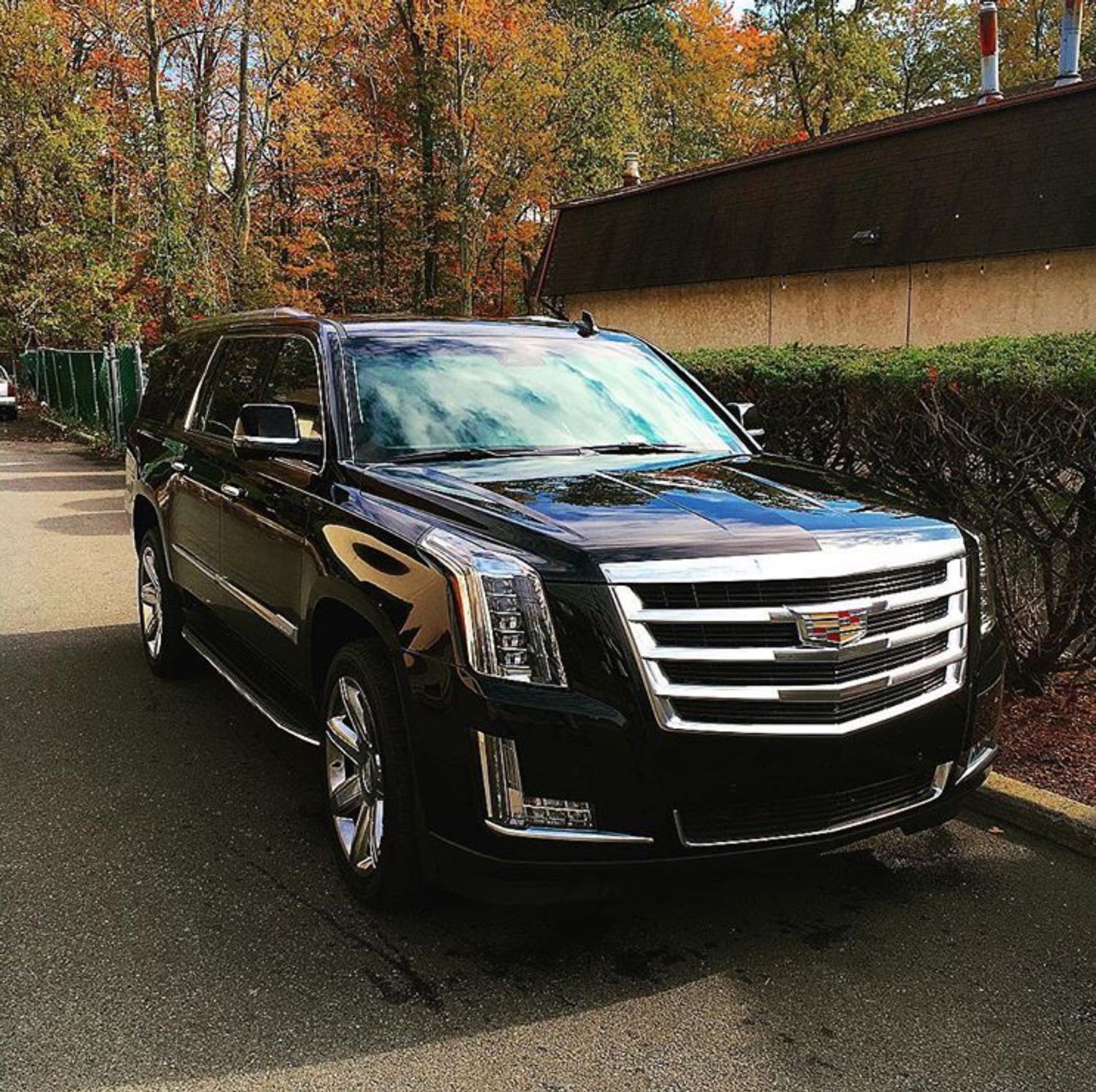 A black cadillac escalade is parked on the side of the road.