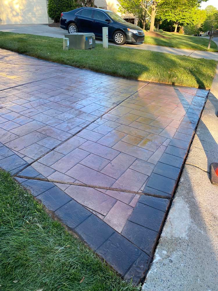 Paver driveway with black border, car parked in the background