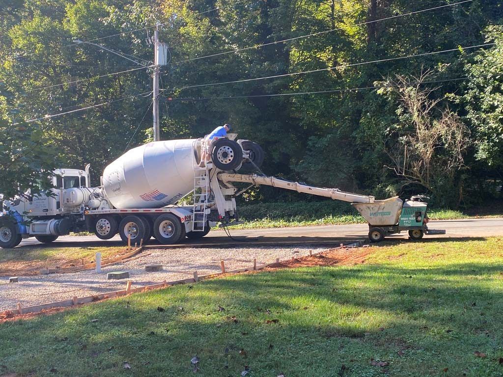 Cement truck pouring concrete into a small motorized cart on a driveway