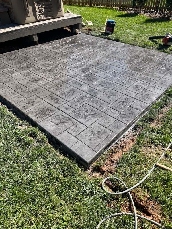 Gray stamped concrete patio next to a wooden deck