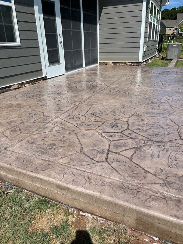 Brown stamped concrete patio outside a house, featuring a stone pattern
