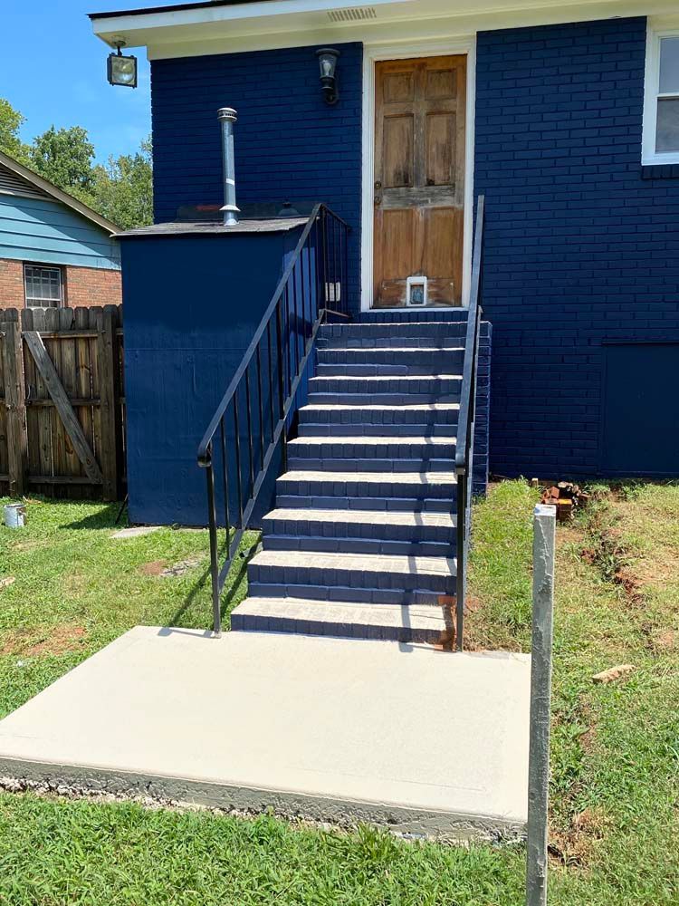 Blue building exterior with stairs, leading to a wooden door