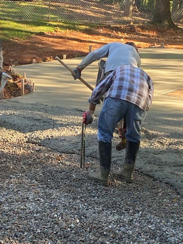Two workers leveling wet concrete with tools on a construction site