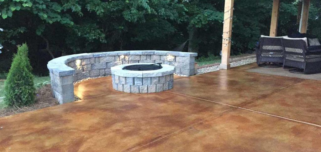 Outdoor patio with fire pit and stone wall, surrounded by trees