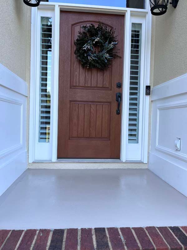 Brown door with a wreath, white trim, and sidelights