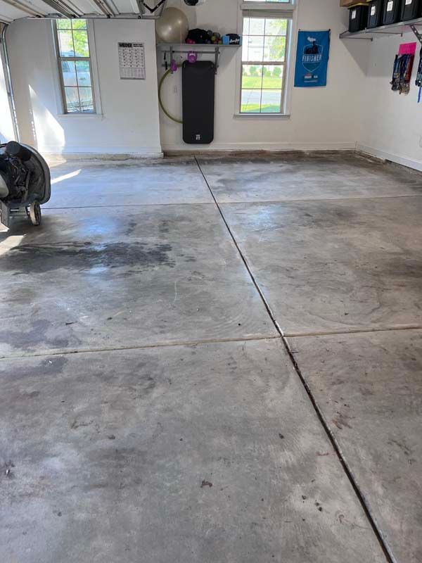 Garage floor, concrete, gray. Two windows, exercise mat on wall