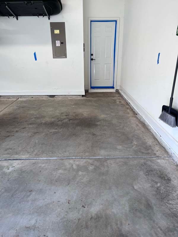 Garage interior with concrete floor, white walls, door, and tools