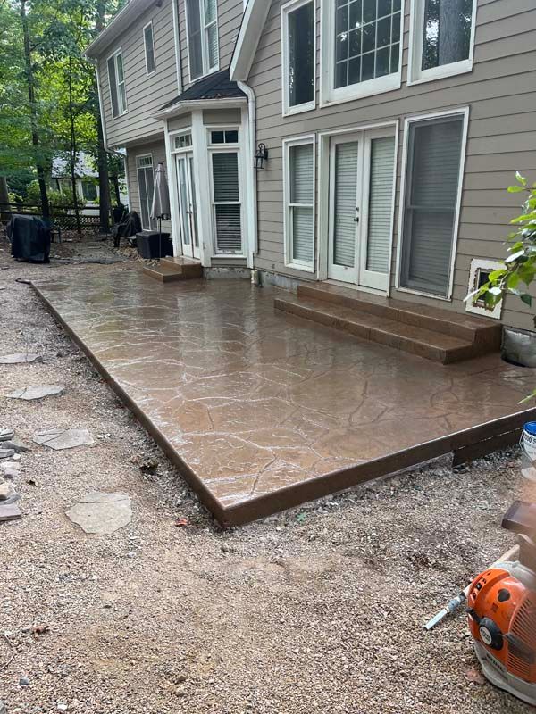Brown stamped concrete patio with steps leading to a house with multiple doors