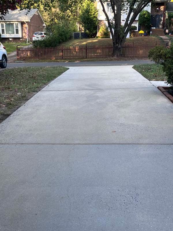 A concrete driveway in front of a house, with grass on either side.
