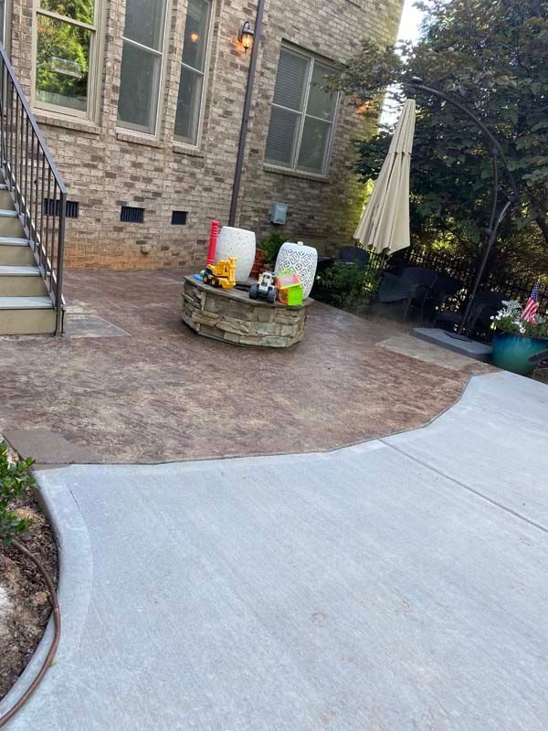 Patio with textured concrete, brick house, fire pit, and umbrella