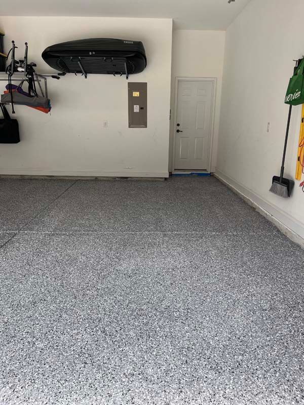 A gray epoxy-floored garage with a white door and walls