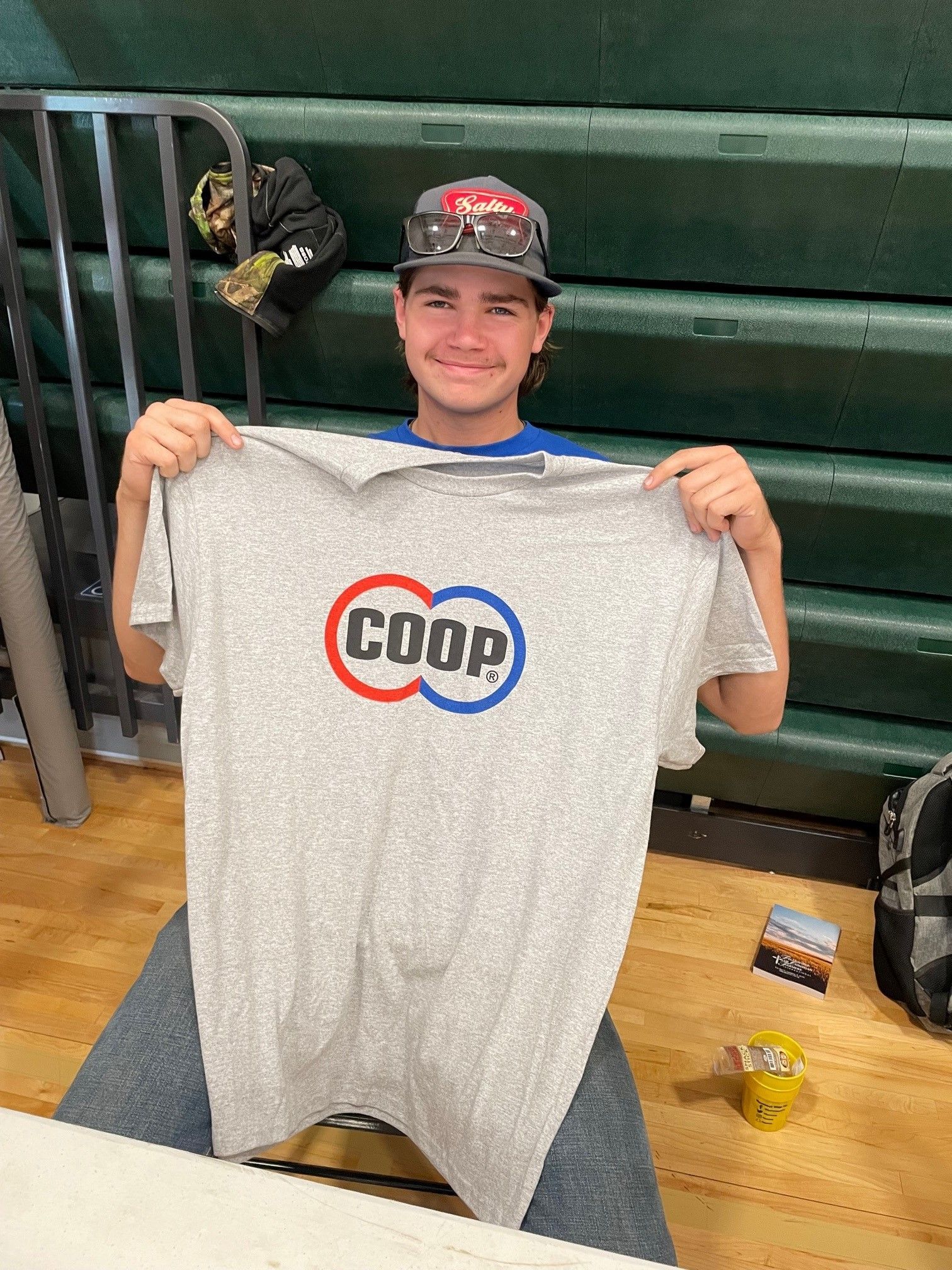 Teen holding a COOP shirt at ag event