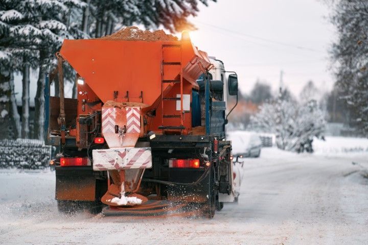 Orange snowplow clearing a snowy road in winter