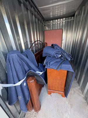 Storage unit with a bed frame, nightstand, and furniture covers.