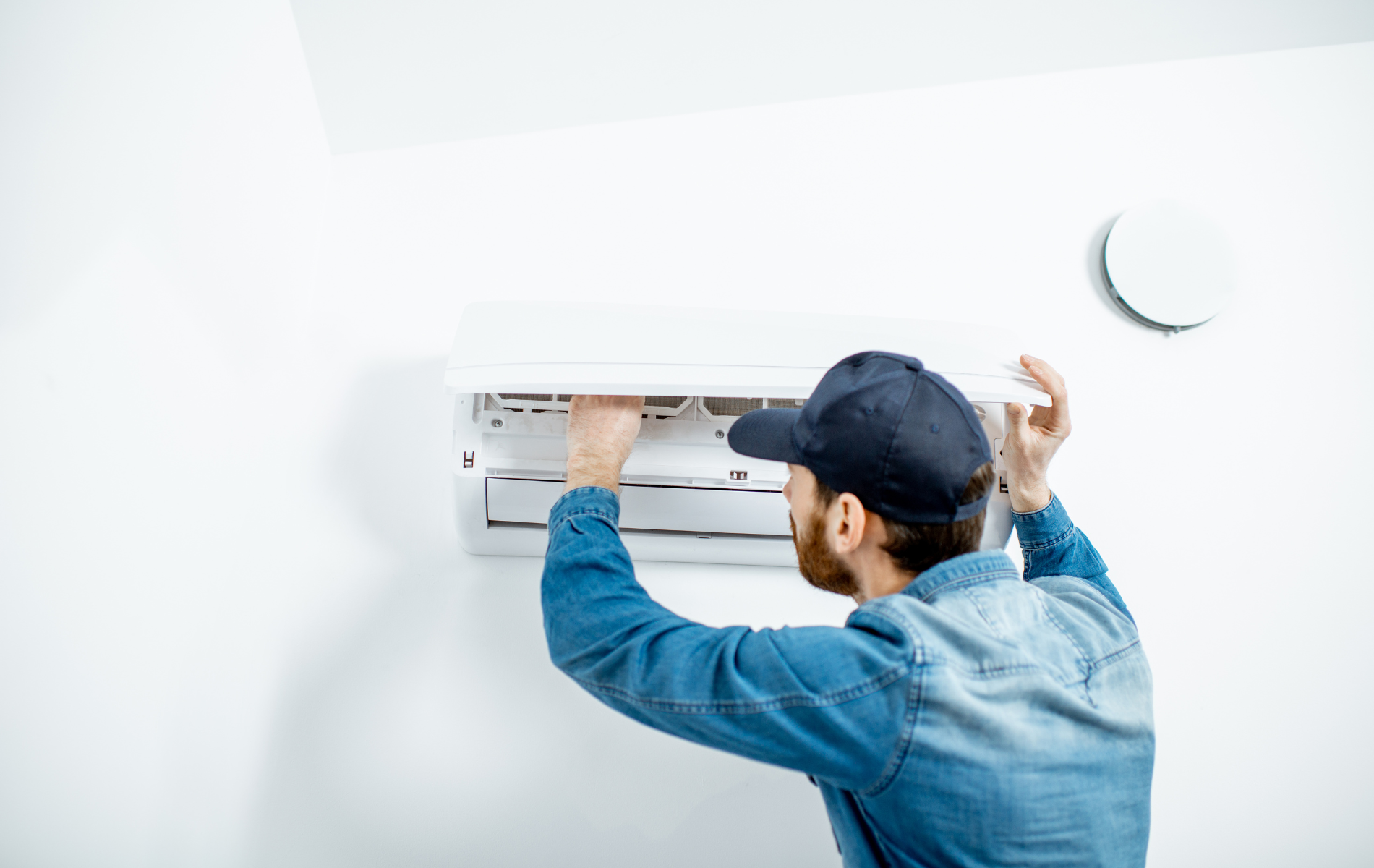 A man is installing an air conditioner on a wall.
