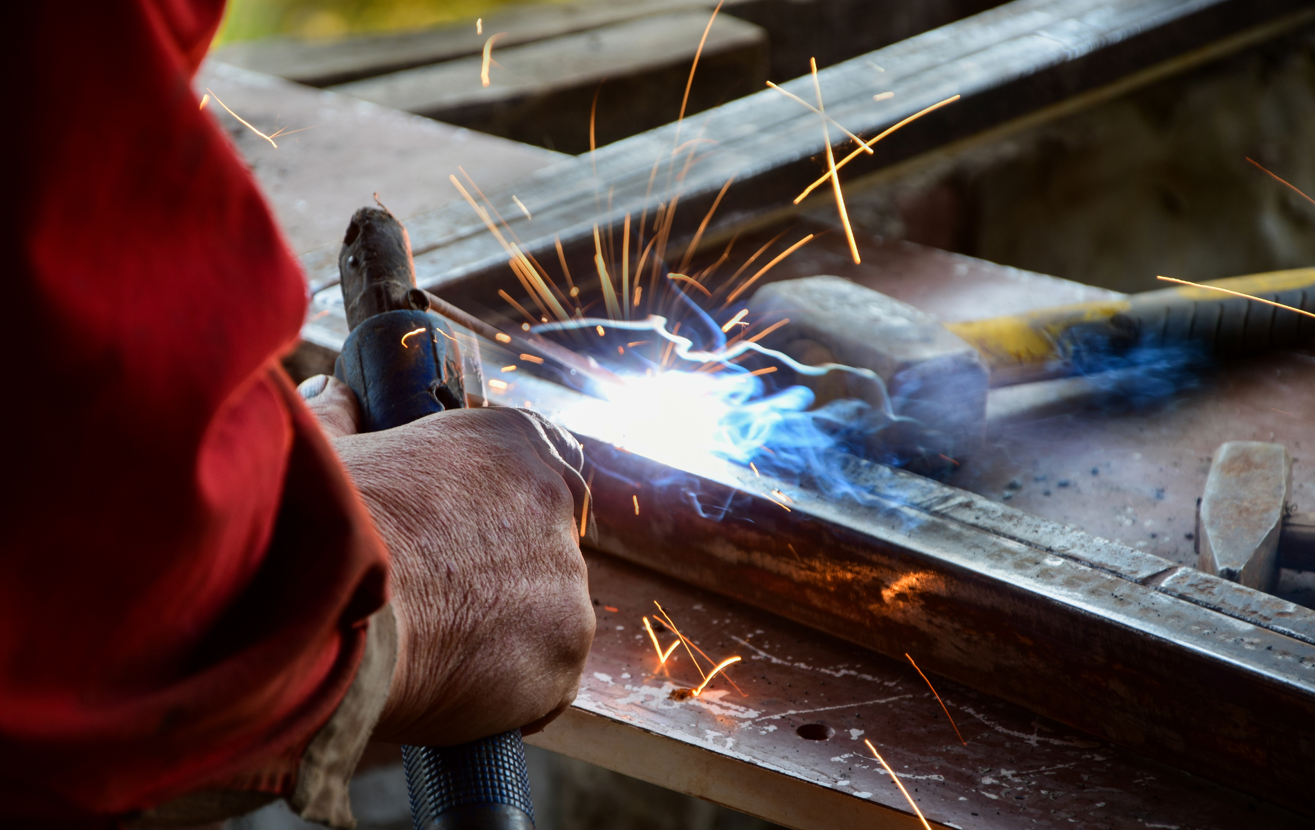 A man is welding a piece of metal with a torch.