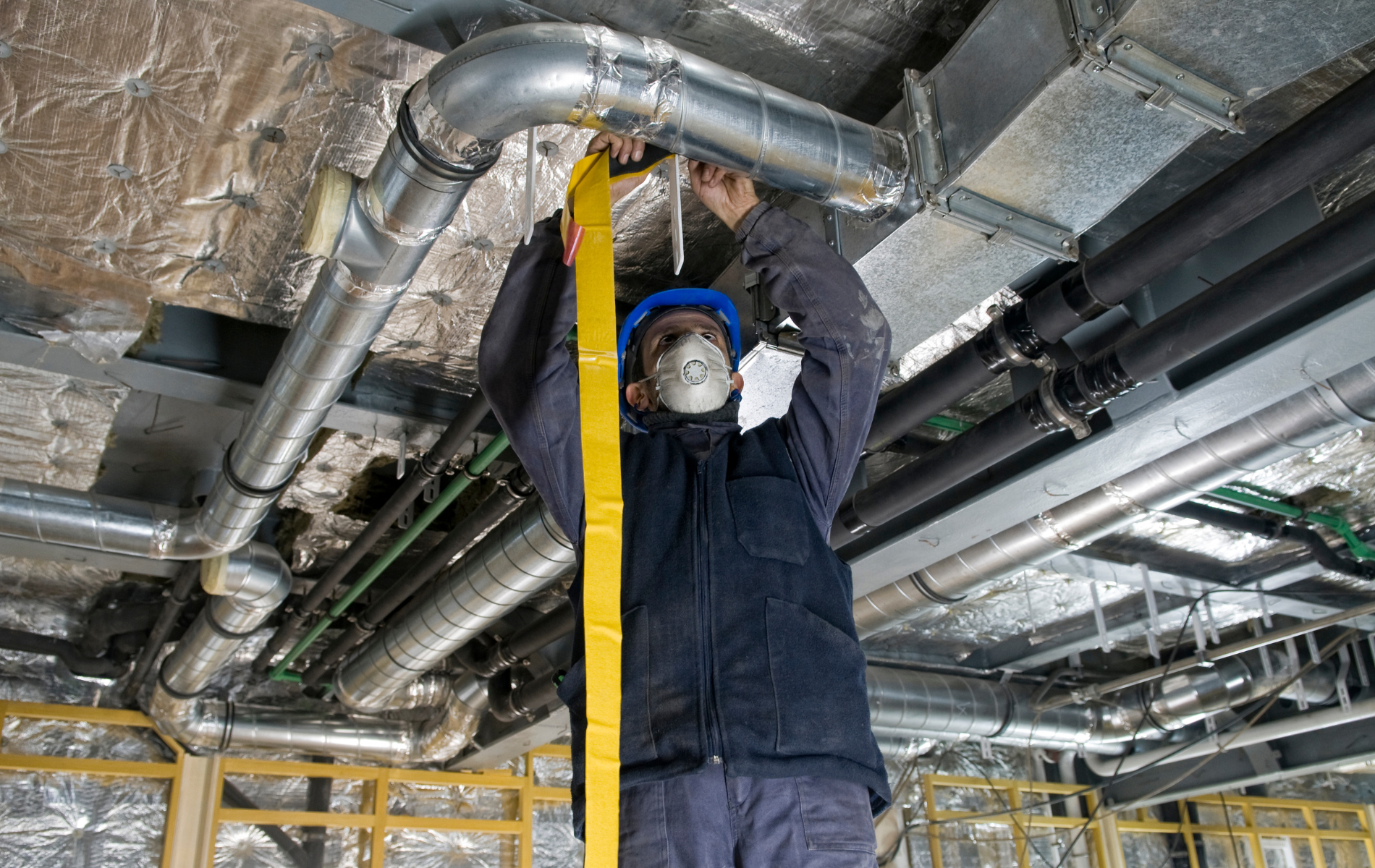 A man is measuring a pipe with a tape measure.