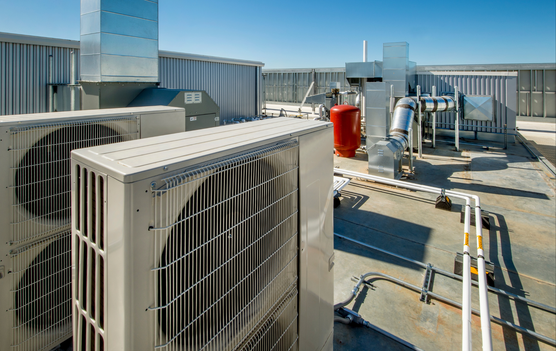 There are a lot of air conditioners on the roof of a building.