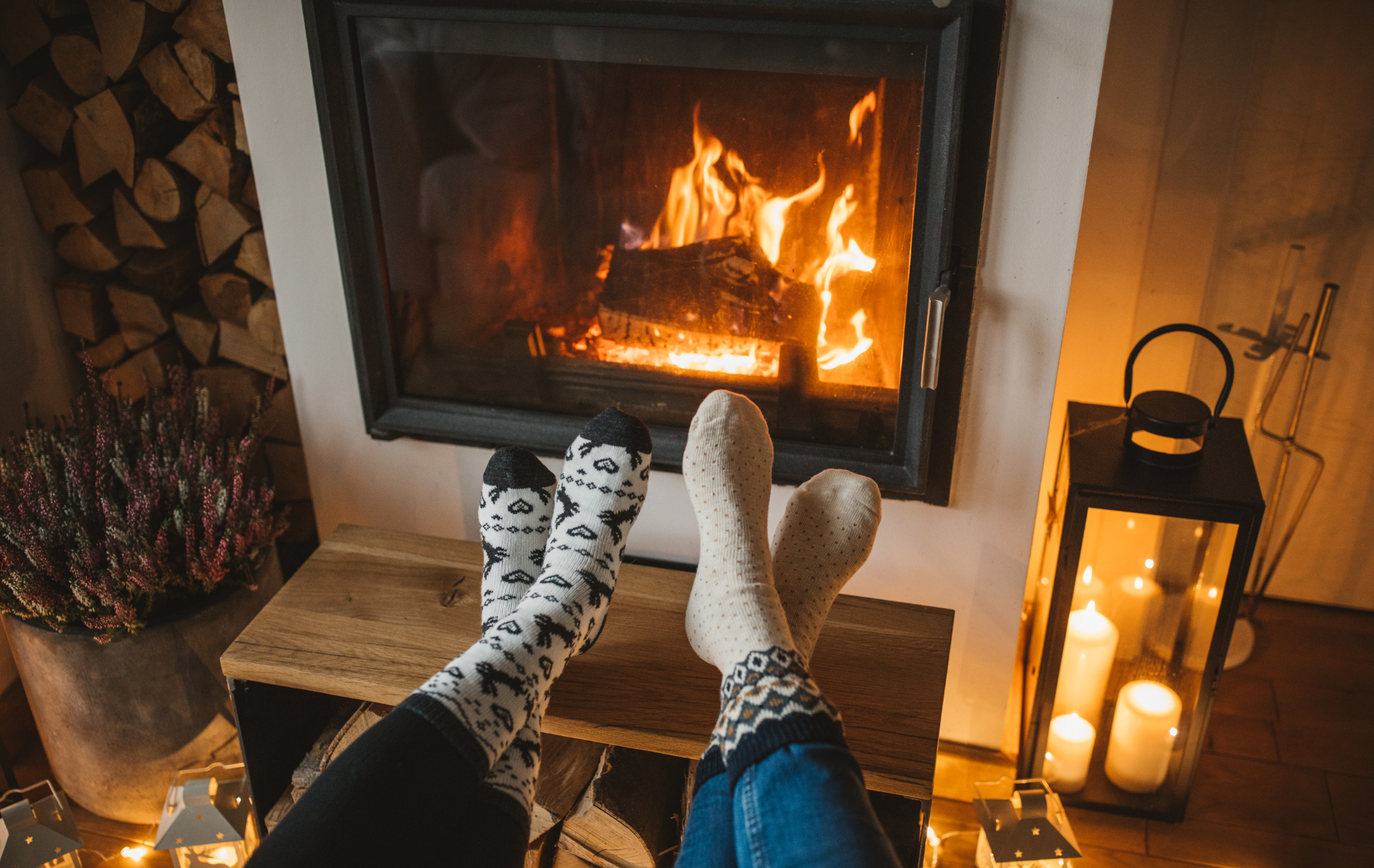 A person is sitting in front of a fireplace with their feet up.