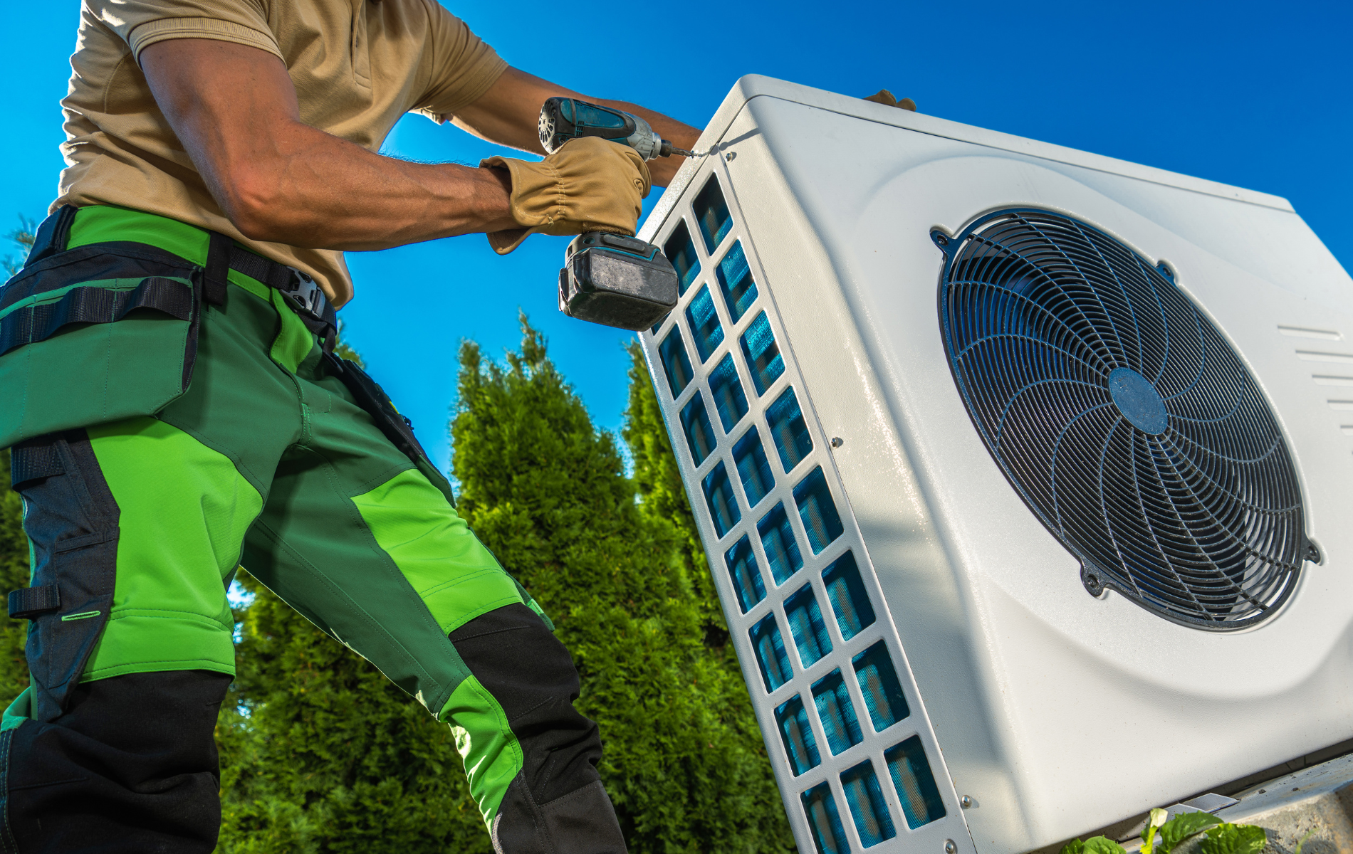 A man is installing an air conditioner with a drill.