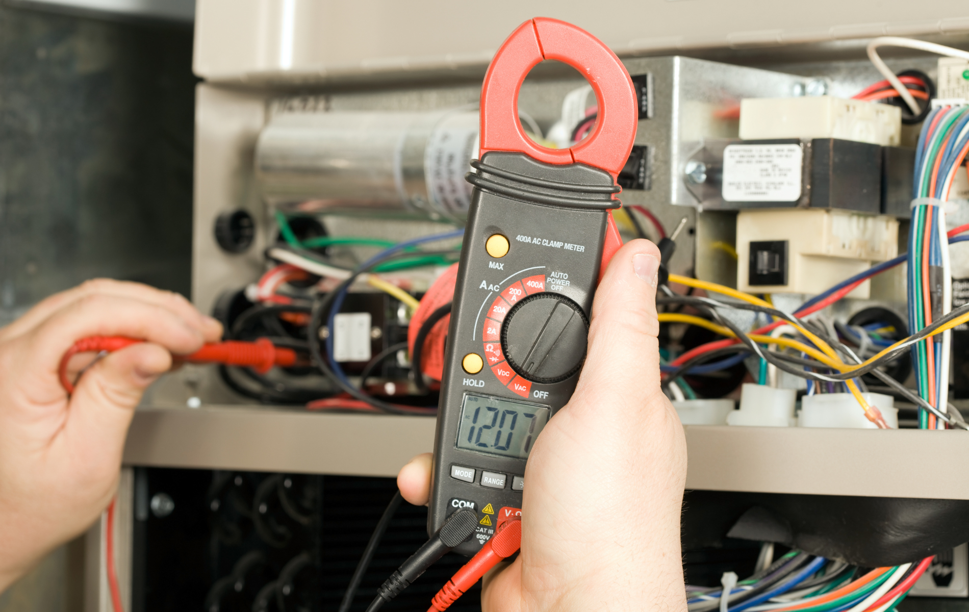 A person is using a clamp meter to measure voltage