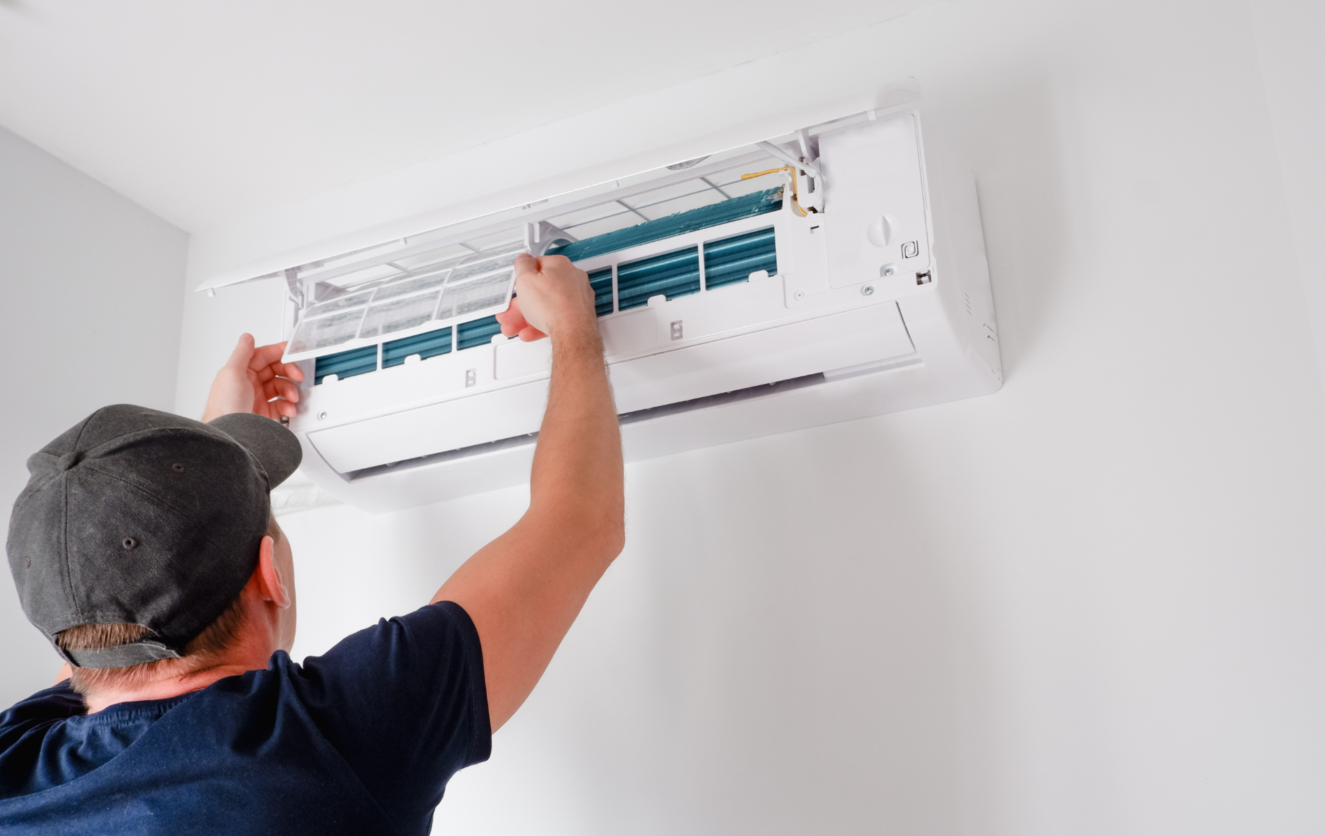 A man is installing an air conditioner on a wall.