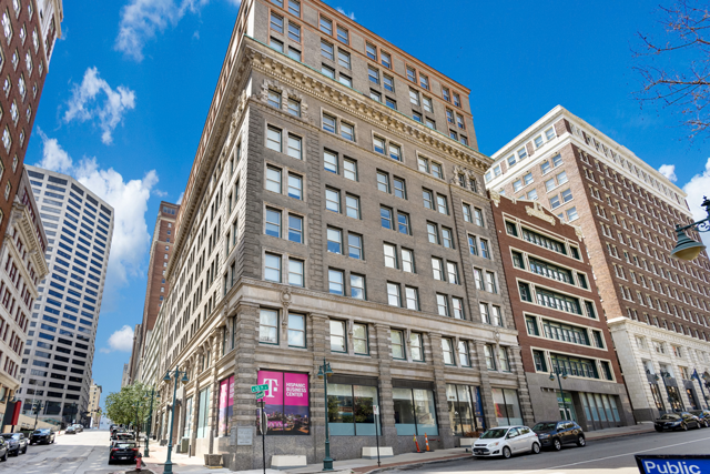 A perspective shot of a tall, historic stone-faced building in an urban setting, featuring a T-Mobile storefront.